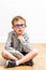 Smart child with eyeglasses thinking, having doubt, sitting crossed legs