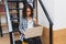 Smart cute young woman sitting on stairs in library, working with laptop. Studying, smart student, surfing in internet