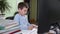 Smart elementary school student learns lessons at home sitting at computer and watches video broadcast of lesson with