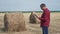 Smart farming agriculture concept. Man farmer worker studying a haystack in a field on digital tablet. Slow motion