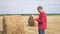 Smart farming agriculture concept. Man lifestyle farmer worker studying a haystack in a field on digital tablet. Slow