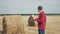 Smart farming lifestyle agriculture concept. man farmer worker studying a haystack in a field on digital tablet. slow