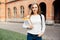 Smart female college student with bag and books on campus outdoors