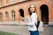 Smart female college student with bag and books on campus outdoors