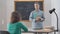 Smart female teacher standing with tablet in classroom answering question of curios student. Portrait of intelligent