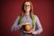 Smart ginger young woman in glasses holding mango on red background