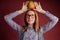 Smart ginger young woman in glasses holding mango on red background