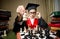 Smart girl in graduation cap making move at chess with horse