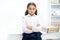 Smart glance. Child girl wears school uniform standing with crossed arms on chest. Schoolgirl smart child looks serious
