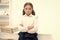 Smart glance. Child girl wears school uniform standing with crossed arms on chest. Schoolgirl smart child looks serious