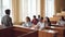 Smart guy student is raising hand and talking to professor while fellow students are listening to them and smiling