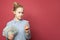 Smart happy cunning young girl showing money us dollars and pointing finger up on pink background