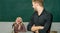 Smart and high trained. Handsome man standing hands crossed in classroom with teacher. High school student saying lesson