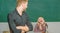 Smart and high trained. Handsome man standing hands crossed in classroom with teacher. High school student saying lesson