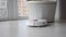 Smart home. Modern cleaning system concept. Round robot vacuum cleaner vacuuming white floor at room. Close up view