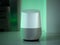 Smart home speaker assistant device in home setting with coloured LED mood lighting - green