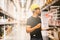 Smart Indian engineer man worker doing stocktaking of product management in cardboard box on shelves in warehouse.