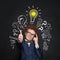 Smart kid student and lightbulb on blackboard background. Happy child showing thumb up. Brainstorming and idea concept