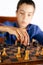 Smart little boy playing chess, a teen grandmaster with vintage chess board