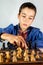 Smart little boy playing chess, a teen grandmaster with vintage chess board