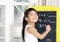 Smart little girl smiling in front of a blackboard.