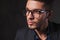 smart man wearing glasses in studio background while looking away