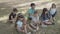 Smart multiethnic kids sitting on ground during lesson in park