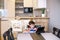 Smart preteen schoolboy doing his homework with digital tablet at home. Child using gadgets on his kitchen to study. Modern