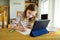 Smart preteen schoolgirl doing her homework with digital tablet at home. Education and distance learning for kids. Homeschooling