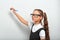 Smart pupil kid girl in eyeglasses looking on the blue wall background