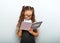 Smart pupil kid girl in eyeglasses looking in the textbook and dooing the exercices on blue background