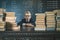 Smart school boy sitting at table with many books