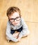 Smart schoolboy with oversized eyeglasses looking up - high angle view