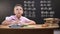 Smart schoolboy solving task, math exercises written on blackboard behind