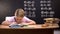 Smart schoolboy solving task, math exercises written on blackboard behind