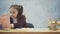 A smart schoolgirl sits at the table and writes homework. During this searches the page in the book