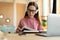 Smart teen girl reading textbook, sitting at table with laptop and studying materials, learning remotely from home