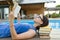 Smart teenage girl in glasses reading book, teenager near house