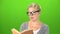 Smart woman in glasses reads a book . Green screen