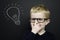 Smart young boy stood infront of a blackboard