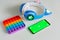 Smartphone with blank green screen mockup with kids headphones and rainbow pop it fidget on gray background