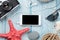 Smartphone and camera on table with starfish and shells