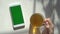 Smartphone in caucasian female hands being held vertically. Green screen. Chroma key. Wooden office desk with cup of tea
