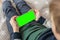 Smartphone with a chromakey in the hands of a child top view close up. Phone a for keying is holding kid