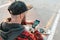 Smartphone and communication. A young guy in a cap, with a beard, uses a smartphone. In the background is a road and a skateboard.