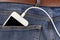 Smartphone with connection USB cable in the back pocket of the jeans closeup