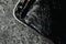 Smartphone with cracked screen on grey stone background, closeup. Device repair