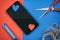 Smartphone and craft paper valentine hearts red and blue on craft desktop with color papers knife, scissors and rope