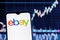 Smartphone with eBay logo on the background of the stock chart