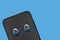 Smartphone with eyes isolated on blue background. The concept of Internet espionage